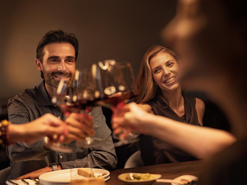 poeple toastibg with red wine filled glasses